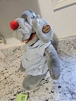Full view of Wrinkles dog puppet standing on countertop showing dress and tag