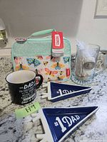 Group of all items: lunch bag, mug, stein, two pennants