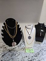 Three necklace stands displaying all five necklaces
