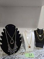 Three necklace display busts showing all five necklaces