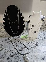 All three necklaces on display stands and countertop