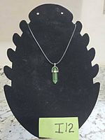 Front view of necklace with green crystal pendant on black cord