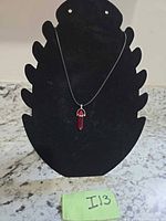Full view of necklace with red point pendant on display form
