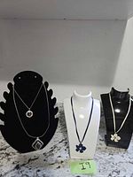Three necklace displays holding the four necklaces in the lot