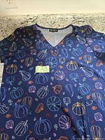Front view of pumpkin print scrub top with size tag A13 visible
