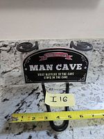 Front view of sign showing graphics and mounting hook with measuring tape for scale