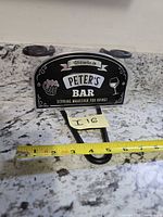Front view of packaged Peter's Bar sign with width measurement tape