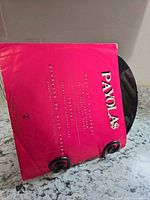 Front of pink sleeve with Payola$ logo and production credits visible, record partially shown