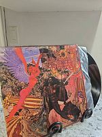 Front cover and exposed vinyl disc displayed on stand