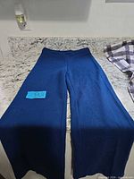 Full view of blue bell-bottom pants laid flat