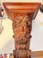 Front view showing full carved bearded head and shelf top