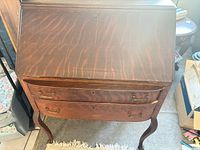 Front view showing drop-front panel, keyhole, two serpentine drawers, brass pulls, cabriole legs