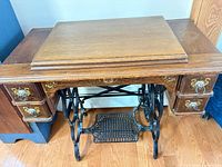 Full view of oak treadle sewing cabinet showing drawers and cast iron base