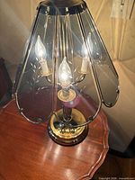 Lamp overall lit on table showing brass base and glass shade