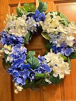 Front view of blue and white artificial hydrangea wreath hanging on door