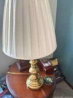 Single brass table lamp with shade on wooden table