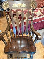Front view of rocking chair showing spindle back, seat and floral crest rail