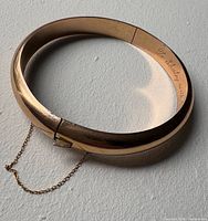 Full view of rose gold bangle showing hinge and safety chain