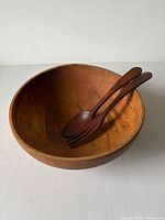 Overhead view of wooden salad bowl with servers inside