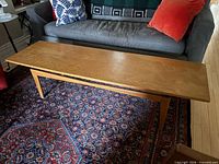 Full view of oak coffee table on rug in front of sofa