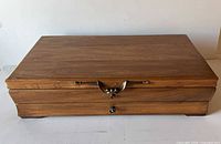 Closed wooden storage chest front view showing brass latch and drawer knob