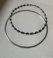 Both bangles laid flat showing designs and size comparison