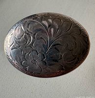 Front view showing etched floral design on oval brooch