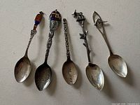 Five sterling silver souvenir spoons laid out