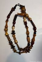 Full view of the necklace coiled to show turned wooden pieces and clasp