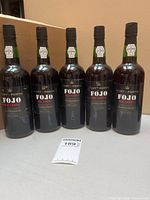 Five Fojo Old Tawny Port bottles standing upright with auction tag
