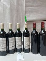 Six bottles standing, showing rear labels of Lecusse and full bottles