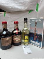 Front view of two Drambuie bottles, one Yellow Chartreuse bottle, and Innis & Gunn beer box with lot tag