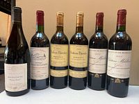 Front view of six wine bottles showing labels and fill levels