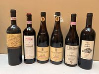 Front view of all six wine bottles showing labels and overall condition