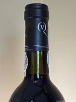 Bottle neck with black capsule and "Q" emblem