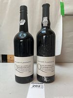 Two bottles showing front labels and embossed crests