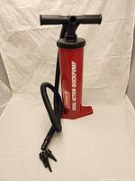 Full view of red Coleman Dual Action QuickPump with hose attached