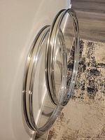 Two chrome 22" drum hoops standing against wall