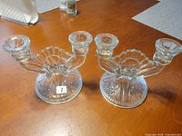 Pair of clear pressed glass double-arm candle holders, top view showing both pieces