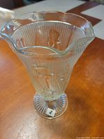 Full view of vase standing upright showing scalloped rim and floral embossing