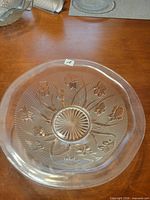 Top view of clear pressed-glass bowl showing iris motif and herringbone ribbing