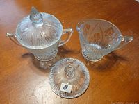 Sugar bowl with lid, creamer and spare lid on tabletop