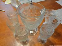 Pitcher surrounded by six glasses showing floral ribbed pattern