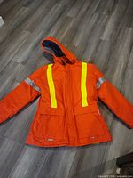Front view of orange WestSafe hi-vis jacket showing reflective vertical stripes, hood, pockets and zipper