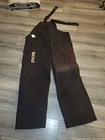 Back view of bib overalls showing leg pockets and swing tags