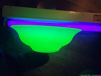 Side view of bowl glowing bright green under UV light