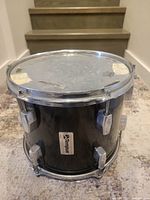 Full view of Tempus tom drum showing black carbon fiber shell, chrome hoops and lugs