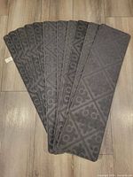 Stack of eleven gray stair treads fanned out showing top pattern