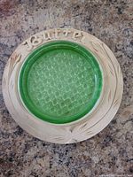 Top view of butter dish showing carved lettering and green glass insert