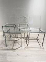 Front angled view of all four clear lucite chairs on chrome frames